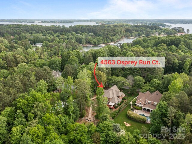 birds eye view of property with a water view and a wooded view