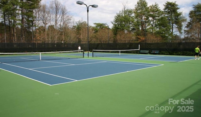 view of tennis court featuring community basketball court and fence