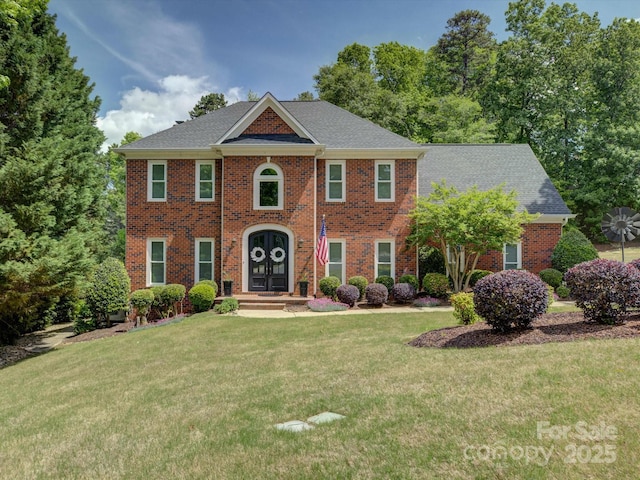 colonial inspired home featuring brick siding and a front yard