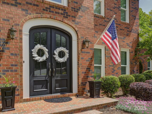 view of exterior entry featuring brick siding and french doors