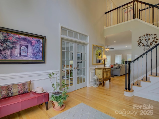 interior space with wainscoting, stairs, french doors, and wood finished floors