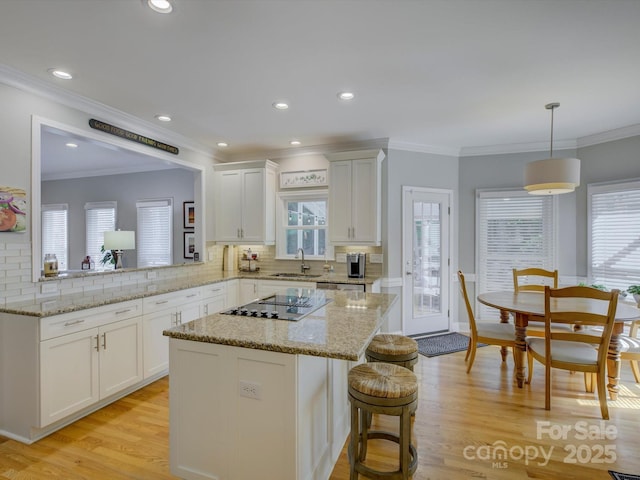 kitchen featuring white cabinets, black electric stovetop, tasteful backsplash, and a sink