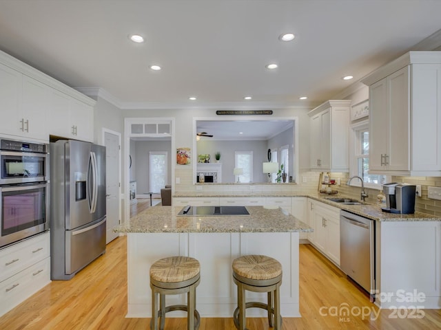 kitchen with a breakfast bar, light wood-style floors, appliances with stainless steel finishes, and tasteful backsplash