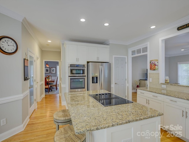 kitchen with light stone counters, crown molding, decorative backsplash, stainless steel appliances, and white cabinetry