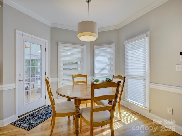 dining room with light wood-type flooring, ornamental molding, baseboards, and plenty of natural light