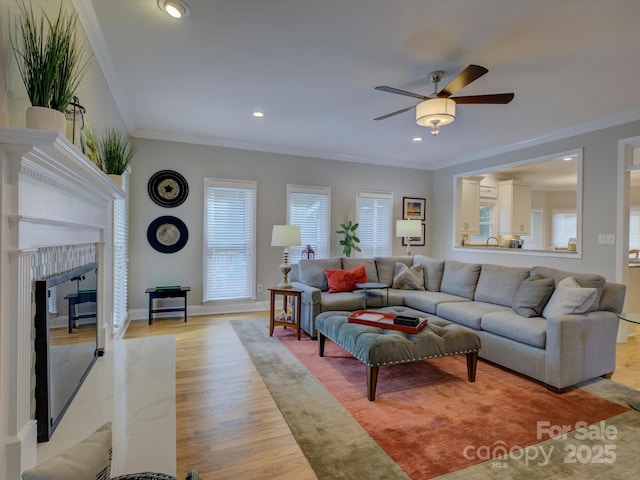living room with a premium fireplace, a ceiling fan, a wealth of natural light, and light wood-style flooring