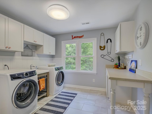 clothes washing area with cabinet space, visible vents, and washing machine and clothes dryer