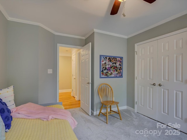 bedroom with a ceiling fan, carpet floors, a closet, crown molding, and baseboards