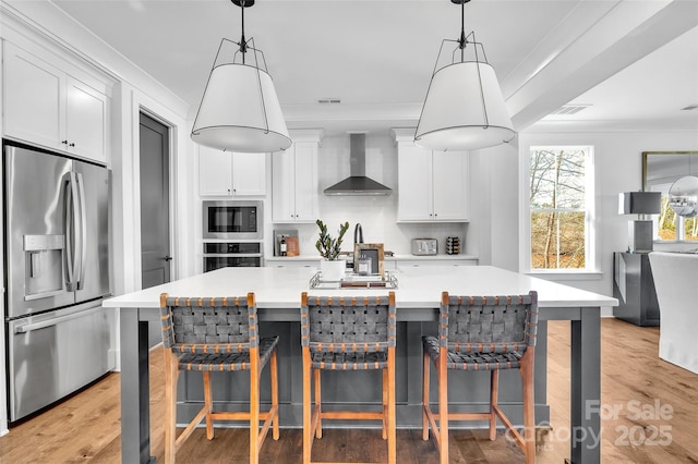 kitchen featuring light countertops, stainless steel appliances, wall chimney exhaust hood, and white cabinetry