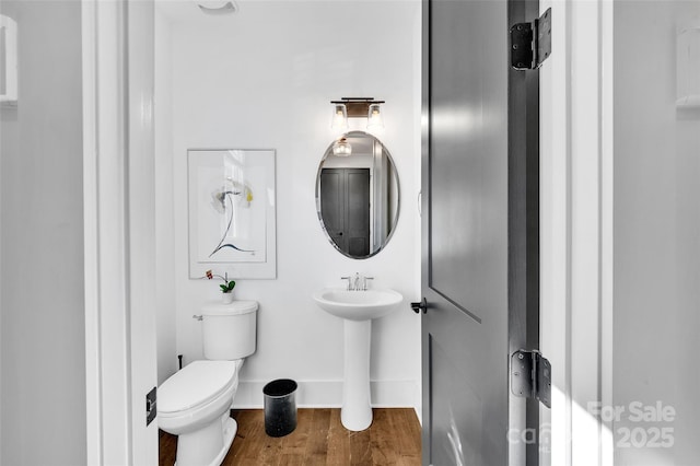 bathroom with toilet, baseboards, and wood finished floors