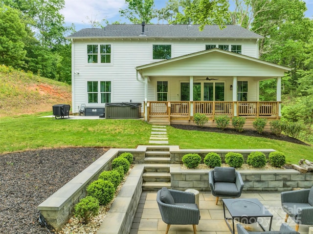 rear view of property featuring a yard, a patio, ceiling fan, and a hot tub