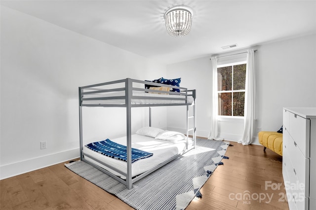bedroom with visible vents, wood-type flooring, baseboards, and a notable chandelier