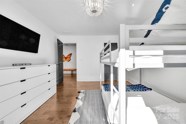 bedroom with baseboards, wood finished floors, and a notable chandelier