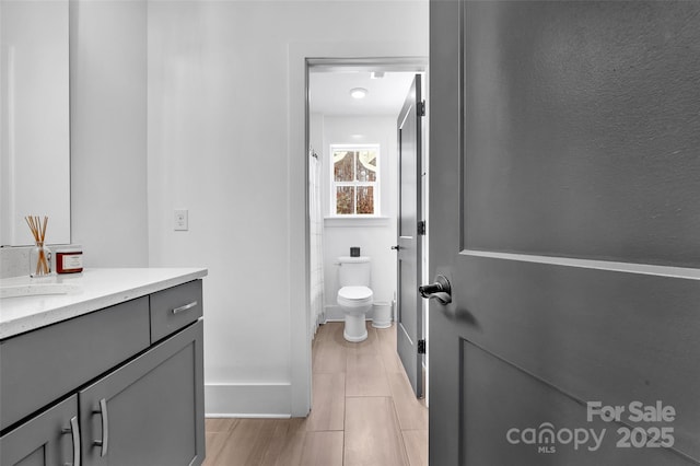 bathroom with vanity, baseboards, and toilet
