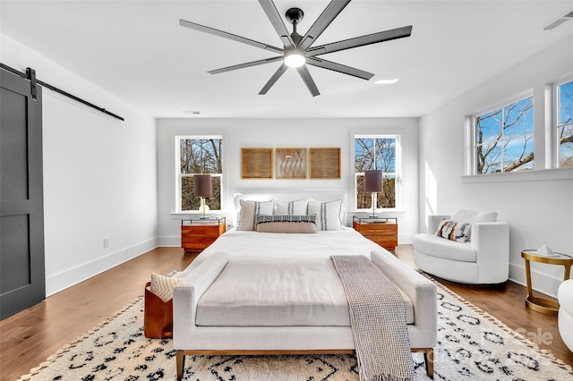 bedroom featuring multiple windows, a barn door, and wood finished floors