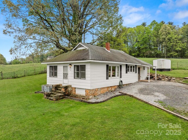 exterior space with a front yard, central air condition unit, fence, and a chimney