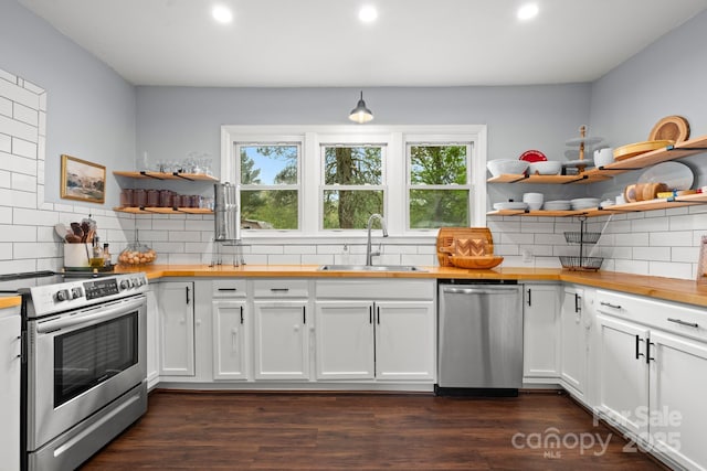 kitchen with a sink, open shelves, wood counters, and appliances with stainless steel finishes