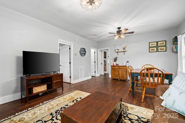 living room featuring a ceiling fan, visible vents, baseboards, and dark wood-type flooring
