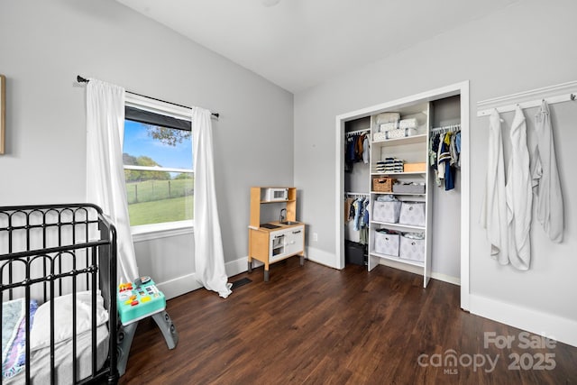 bedroom featuring a closet, dark wood-style floors, and baseboards
