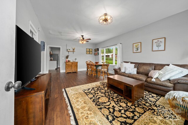 living room with baseboards, ceiling fan, and dark wood-type flooring