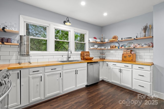 kitchen with butcher block countertops, open shelves, appliances with stainless steel finishes, backsplash, and a sink