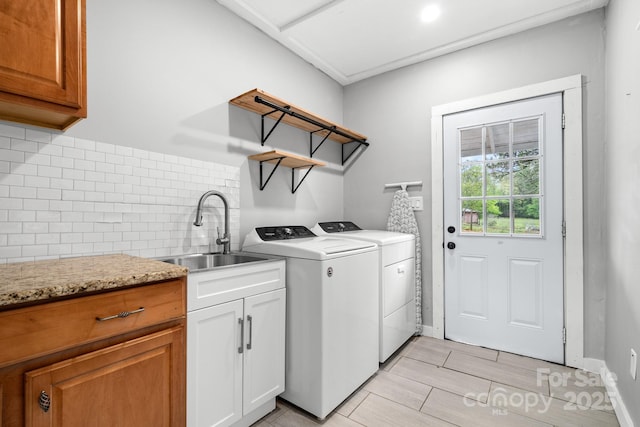 washroom featuring cabinet space, washing machine and clothes dryer, light wood-style flooring, and a sink