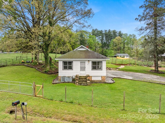 rear view of house featuring a yard, central AC, and fence