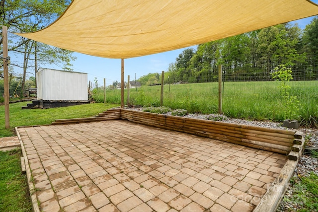 view of patio featuring an outdoor structure, a shed, and fence