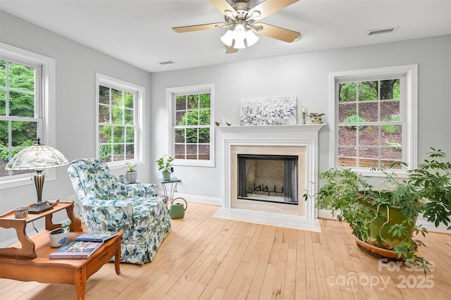 sitting room featuring a ceiling fan, visible vents, a fireplace with flush hearth, hardwood / wood-style flooring, and baseboards