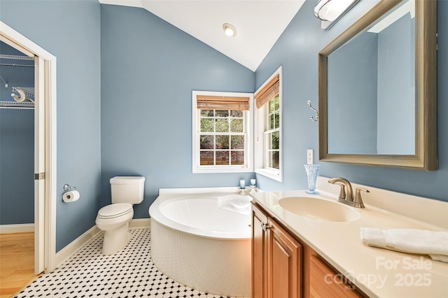 full bathroom with a garden tub, vaulted ceiling, vanity, baseboards, and toilet
