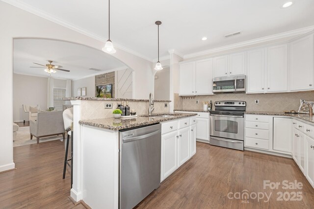 kitchen featuring wood finished floors, stainless steel appliances, white cabinets, a sink, and visible vents