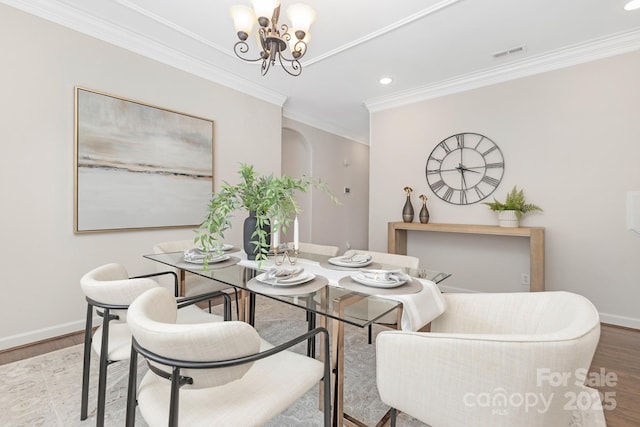 dining area with an inviting chandelier, wood finished floors, visible vents, and ornamental molding
