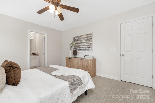 bedroom with a ceiling fan, baseboards, light colored carpet, and ensuite bath