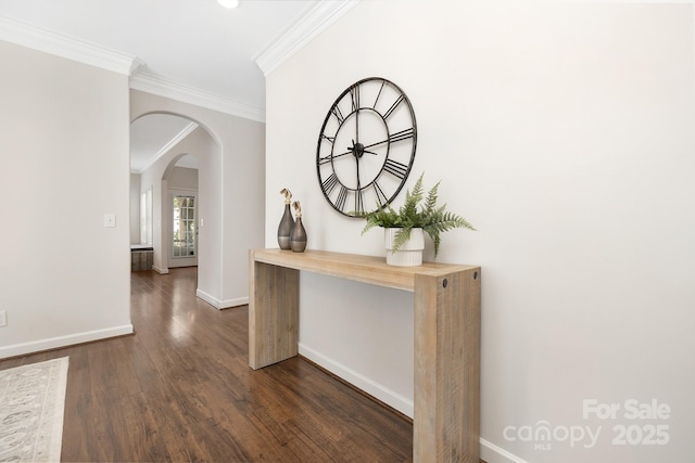 corridor featuring ornamental molding, dark wood-style floors, arched walkways, and baseboards