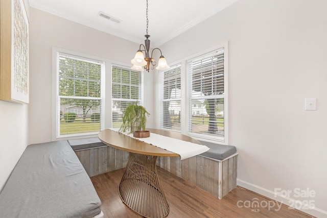 dining space with breakfast area, a notable chandelier, crown molding, visible vents, and wood finished floors