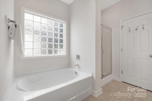 full bath featuring a garden tub, a shower stall, tile patterned flooring, and baseboards