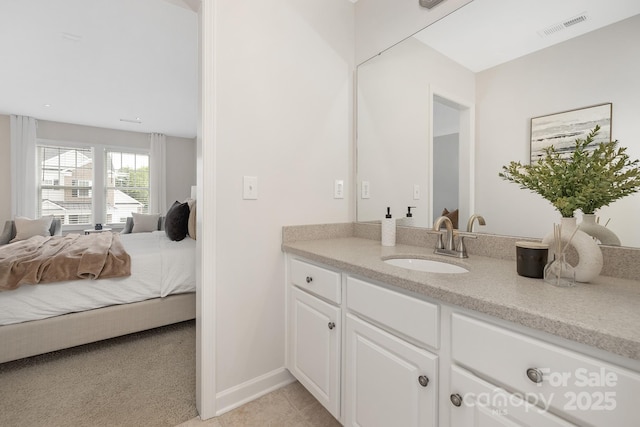 ensuite bathroom featuring vanity, tile patterned floors, ensuite bath, visible vents, and baseboards