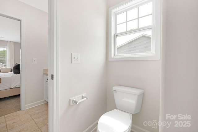 ensuite bathroom with ensuite bathroom, baseboards, toilet, tile patterned floors, and vanity
