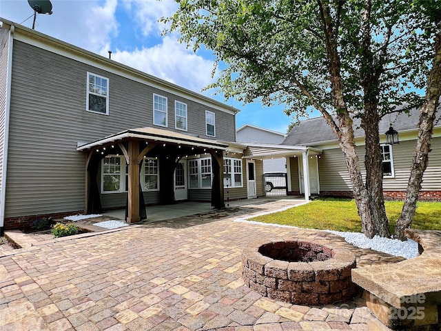 rear view of house with a fire pit and a patio