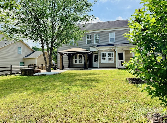 rear view of property featuring fence, a gazebo, a patio area, and a yard