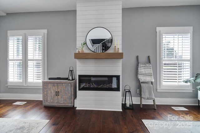 living room with a large fireplace, visible vents, wood finished floors, and baseboards