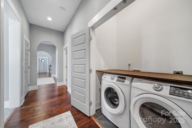 clothes washing area with arched walkways, laundry area, washing machine and dryer, baseboards, and dark wood-type flooring