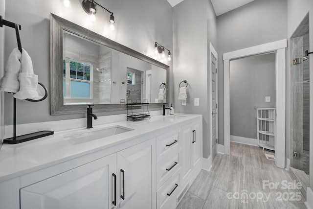 bathroom featuring double vanity, a tile shower, and a sink