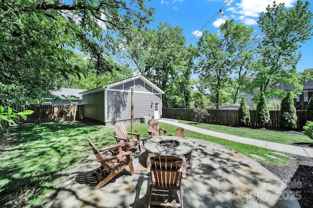 view of patio with an outdoor fire pit, an outbuilding, and a fenced backyard