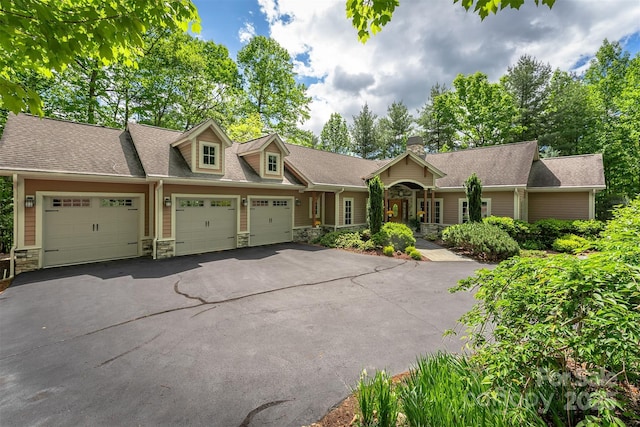 168 Chattooga Run, Hendersonville, NC 28739 - view of front of house featuring stone siding, an attached garage, driveway, a chimney, and roof with shingles