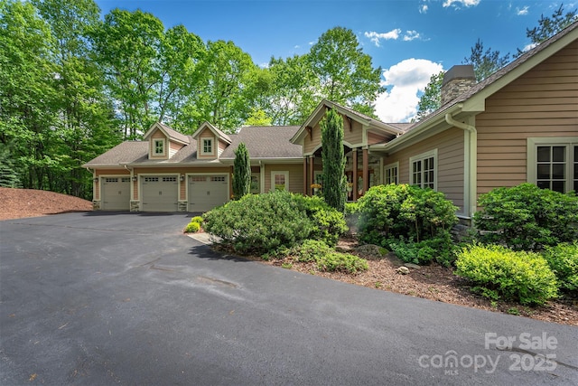 168 Chattooga Run, Hendersonville, NC 28739 - view of front of house with an attached garage, asphalt driveway, a chimney, and roof with shingles