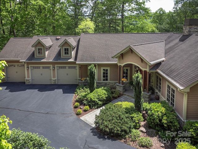 168 Chattooga Run, Hendersonville, NC 28739 - view of front of home featuring stone siding, driveway, a garage, a shingled roof, and a chimney