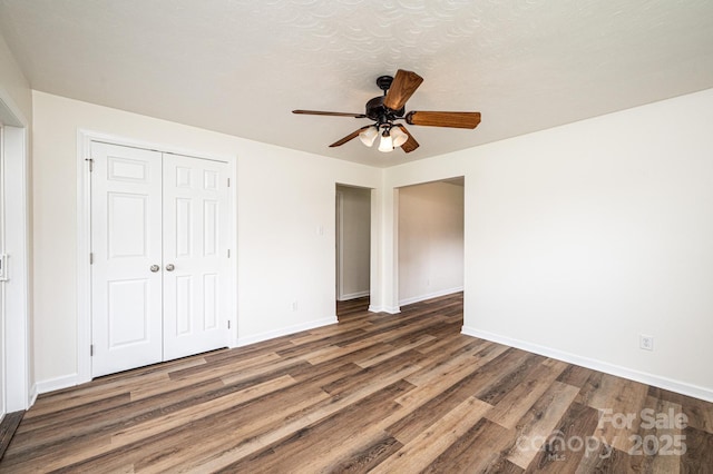 unfurnished bedroom with baseboards, ceiling fan, wood finished floors, and a closet