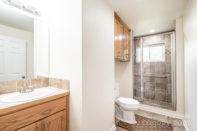 bathroom featuring a stall shower, vanity, tile patterned floors, baseboards, and toilet