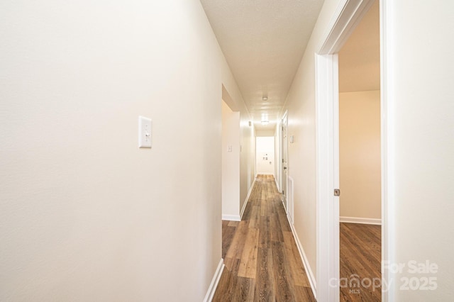 hallway featuring baseboards and dark wood finished floors